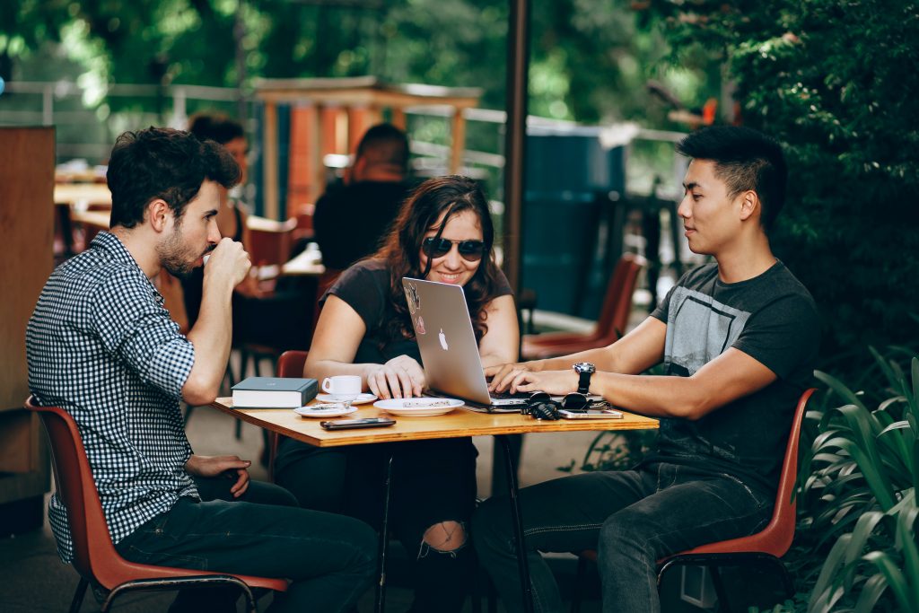 Young people sit at a cafe, drink coffee, talk and laugh